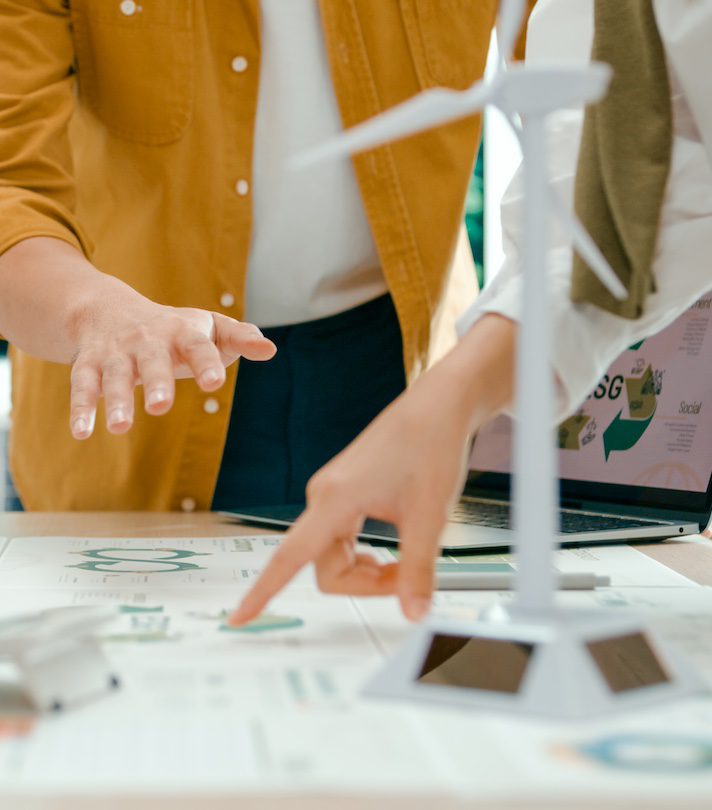 Closeup of team members examine ESG-related documents, pointing and discussing investment strategies for sustainable and renewable energy resources. Eco-Friendly Business Discussing ESG Goals.